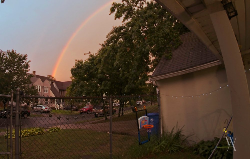 A rainbow appears in the midst of a thunderous evening.